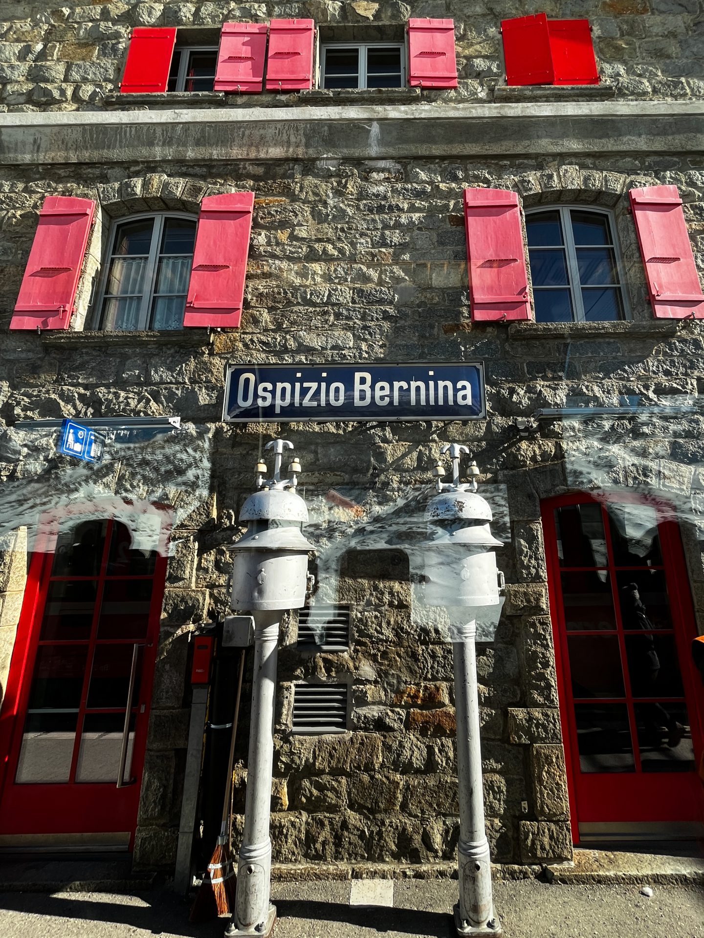 Stone building with red shutters with sign reading "Ospizio Bernina"