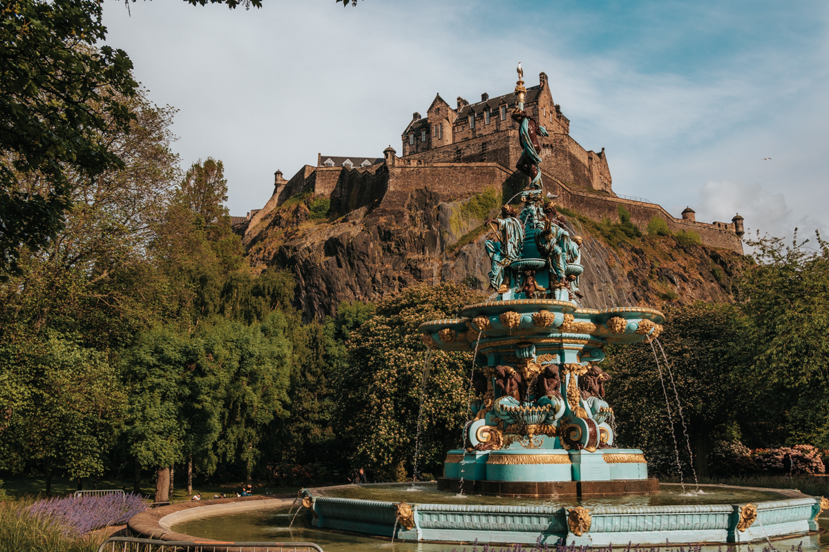 Gold and teal fountain in front of castle on a hill. Edinburgh Castle and Ross Fountain.