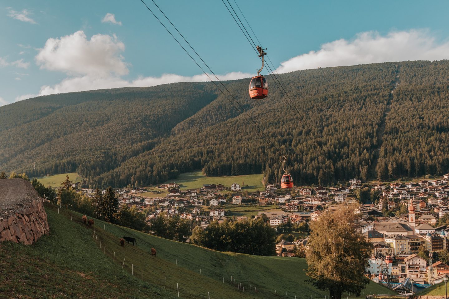 Red cable cable car above alpine town in Ortisei, Italy