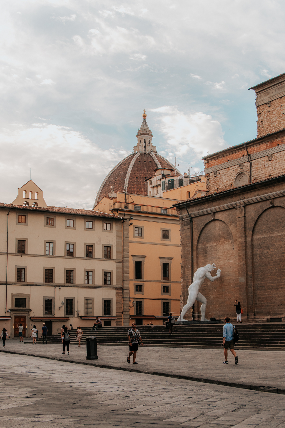 Historic neighborhood with domed church and Renaissance statue against a building. Where to stay in Florence: San Lorenzo neighborhood